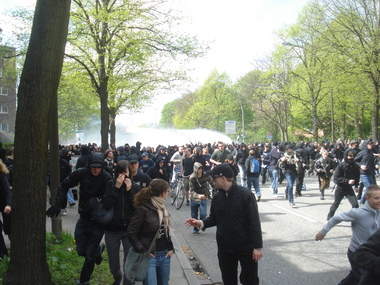 Wasserwerfer im Hintergrund, Demonstranten laufen weg